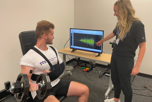 Student working with patient lifting a weight